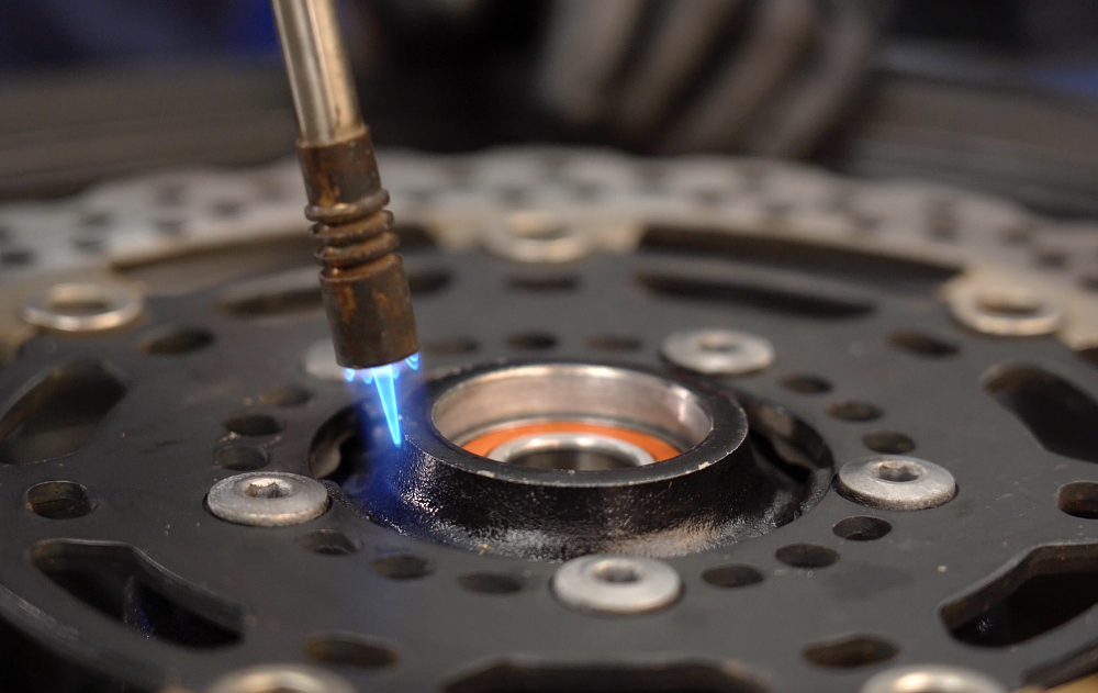 Heating motorcycle hub with a propane torch prior to bearing replacement