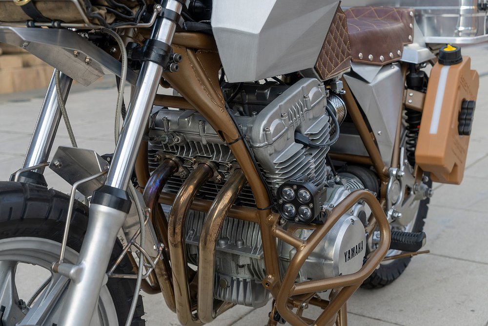 side view of the mostly bare metal motorcycle with brown leather seat and accents
