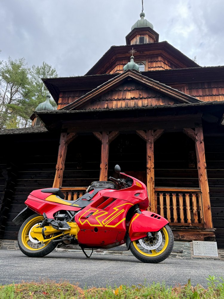 red and yellow K1 parked in front of an old wooden temple building