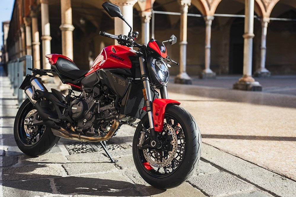 a red Ducati Monster parked on a street in Spain