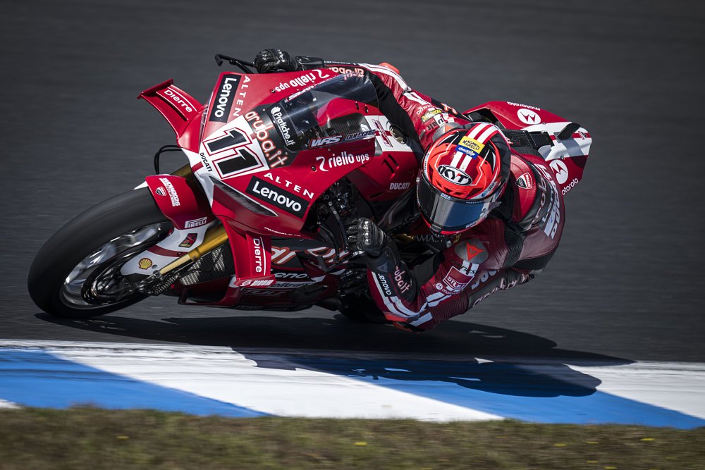 Bulega on the red Ducati dragging a knee in a corner of the Phillip Island track