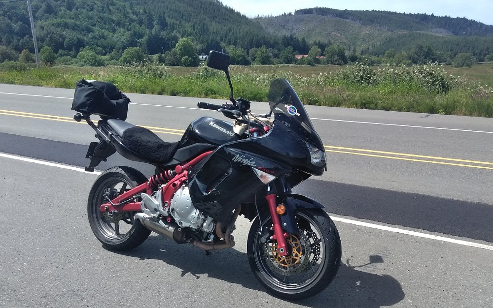 black Kawasaki Ninja 650 with a red frame parked along a country highway