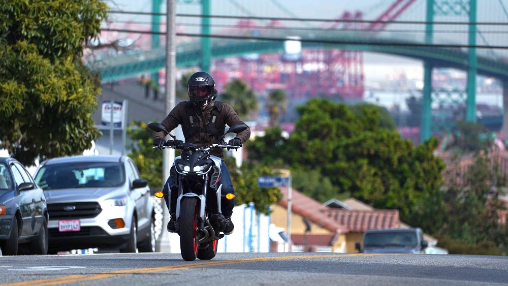 A Yamaha MT-09 riding along a city street with a bridge in the background
