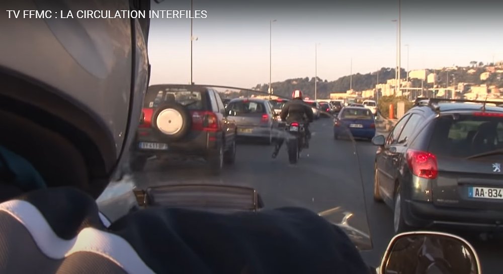 motorcyclist wags his foot to acknowledge a car driver
