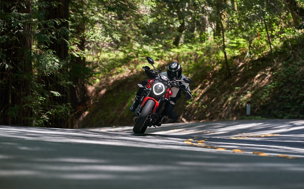 A female rider riding through a tight corner in the woods on the Ducati Monster