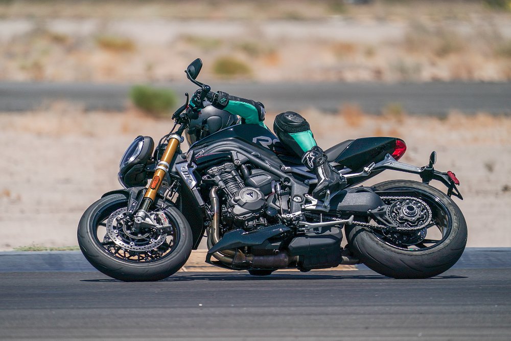 Female rider leans into a corner on the racetrack on board the Triumph Speed Triple 1200 RS motorcycle.