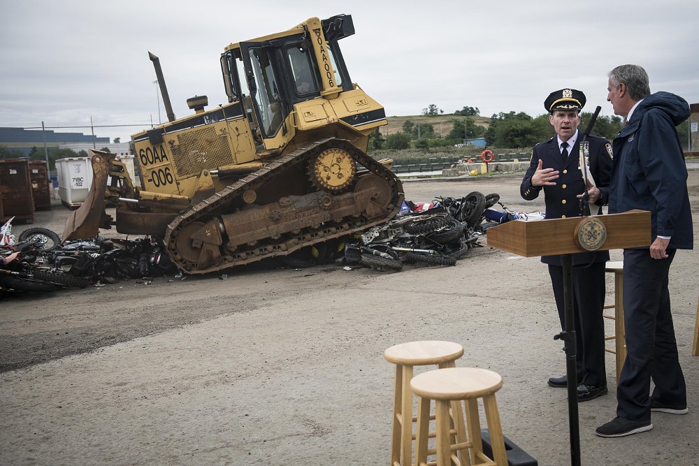 New York mayor and police in front of bulldozer crushing motorcycles