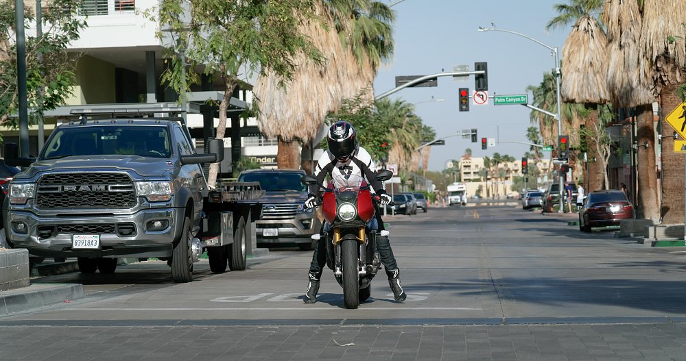 A female rider on board the Speed Triple 1200 RR on city streets is tip toeing at a stop light