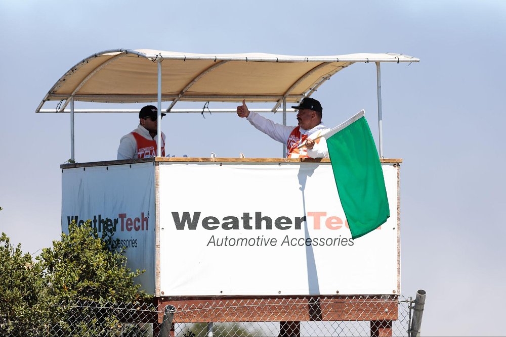 A professional flag marshal displays the green flag at the main tower at Laguna Seca raceway