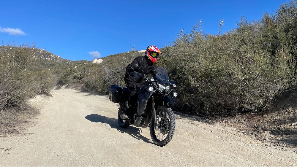 A male rider is on the full size KLR 650 Adventure model riding down a truck trail