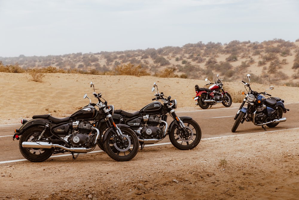 4 different colorways of the royal enfield super meteor 650 in a desert landscape - blue, black, red and green