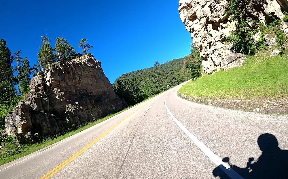 sunny open road ahead with the rider's shadow on the road