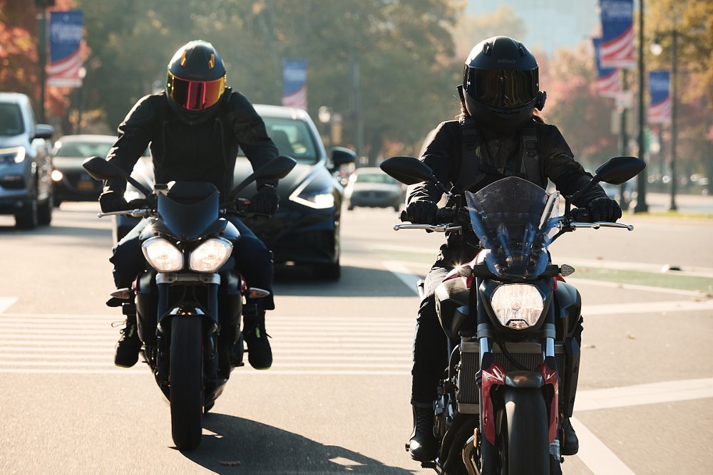 two riders on the street in traffic