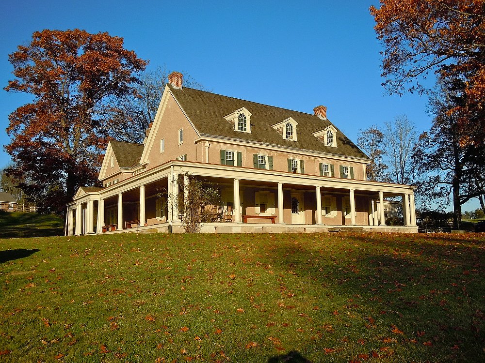 A photo of the colonial style PennyPacker residence with trees in fall colors and bright blue sky