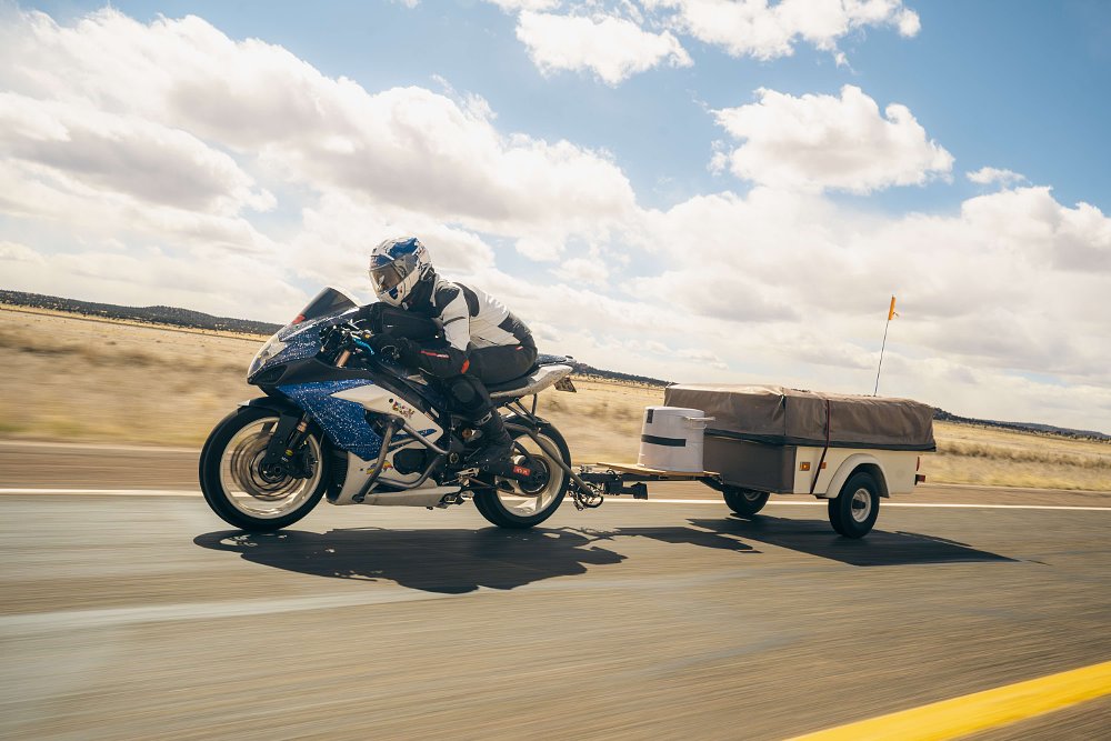 A 2006 Suzuki GSX-R1000 towing a camping trailer, with the rider tucked in.