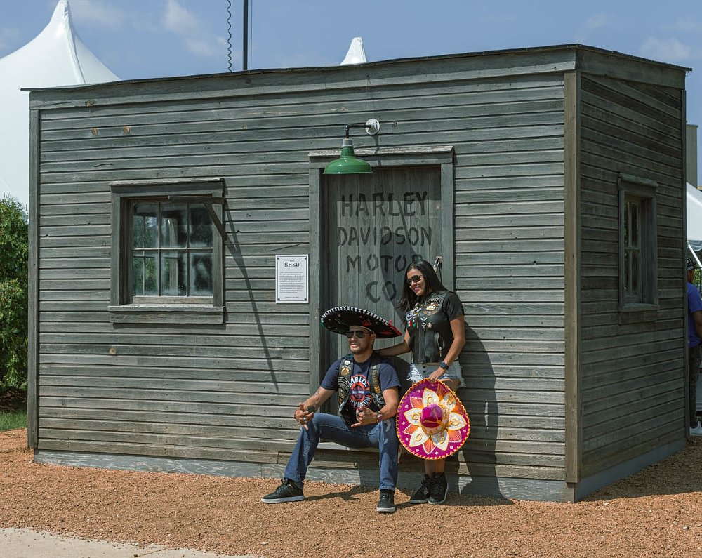 two people posing in front of the replica shed