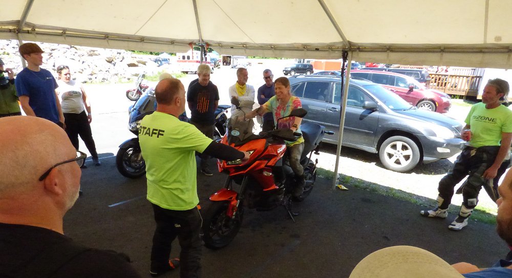 An instructor shows a female student the proper riding position on a stationary motorcycle