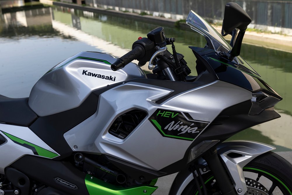A close up view of the side fairing that has a peak of the radiator and battery warning stickers on the Ninja 7 Hybrid motorcycle
