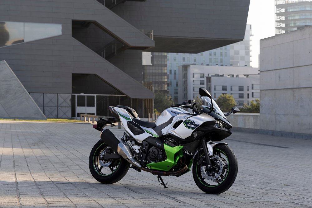 The Kawasaki Ninja 7 Hybrid motorcycle is parked in front of a famous art museum concrete building in Barcelona Spain