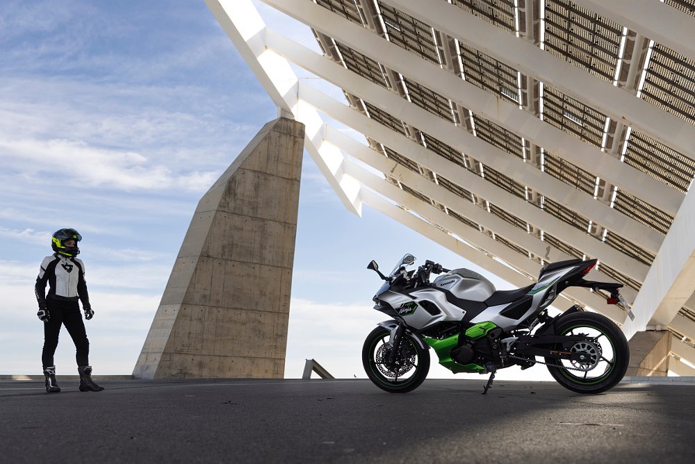 a static shot of the ninja 7 hybrid parked under a huge solar panel array with female rider walking up to it