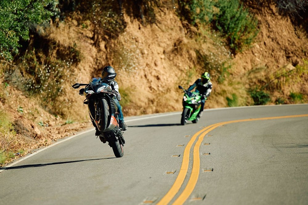CFMOTO 450SS doing a wheelie on a mountain road