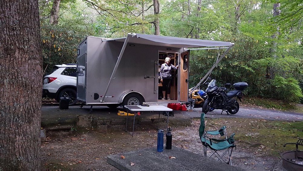 the trailer set up in the campground with motorcycles unloaded