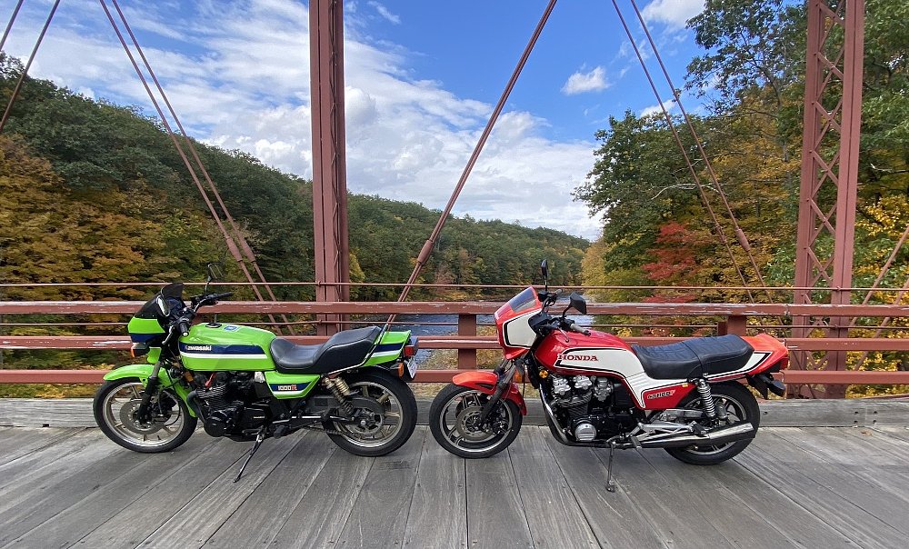 a 1983 Kawasaki and a 1983 Honda parked on an old bridge in New England in the fall
