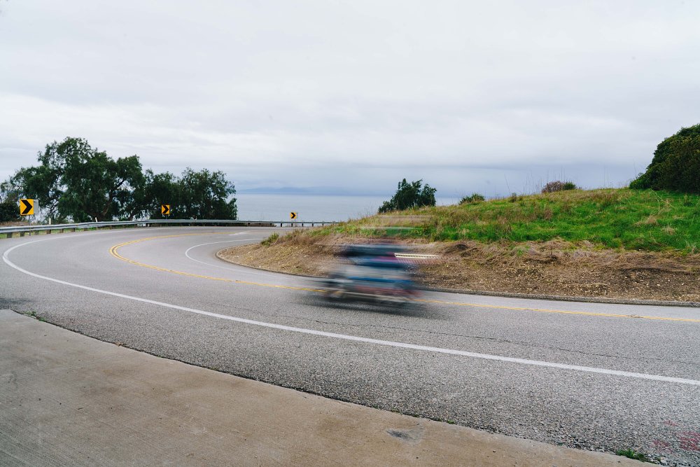 2023 BMW M 1000 R blurred in the foreground, riding through a curve on a mountain road.
