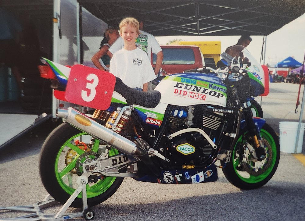 young Andrew posing with a vintage Kawasaki race bike