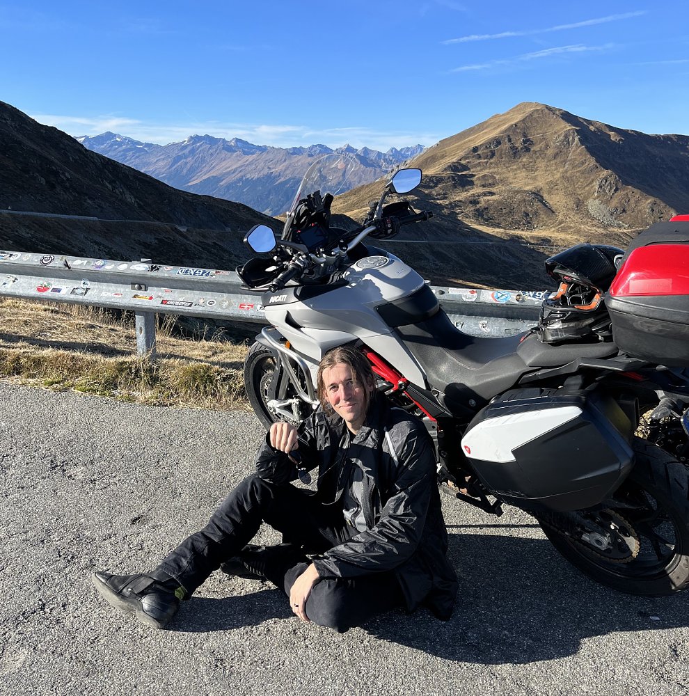 sitting on the ground in front of the Multistrada high on an Italian mountain road