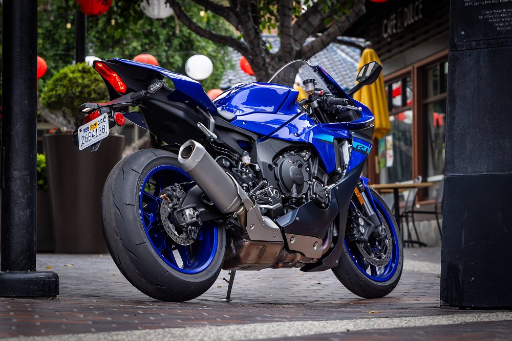 Rear three-quarter view of a Yamaha R1 parked in courtyard with Japanese lanters in the background.