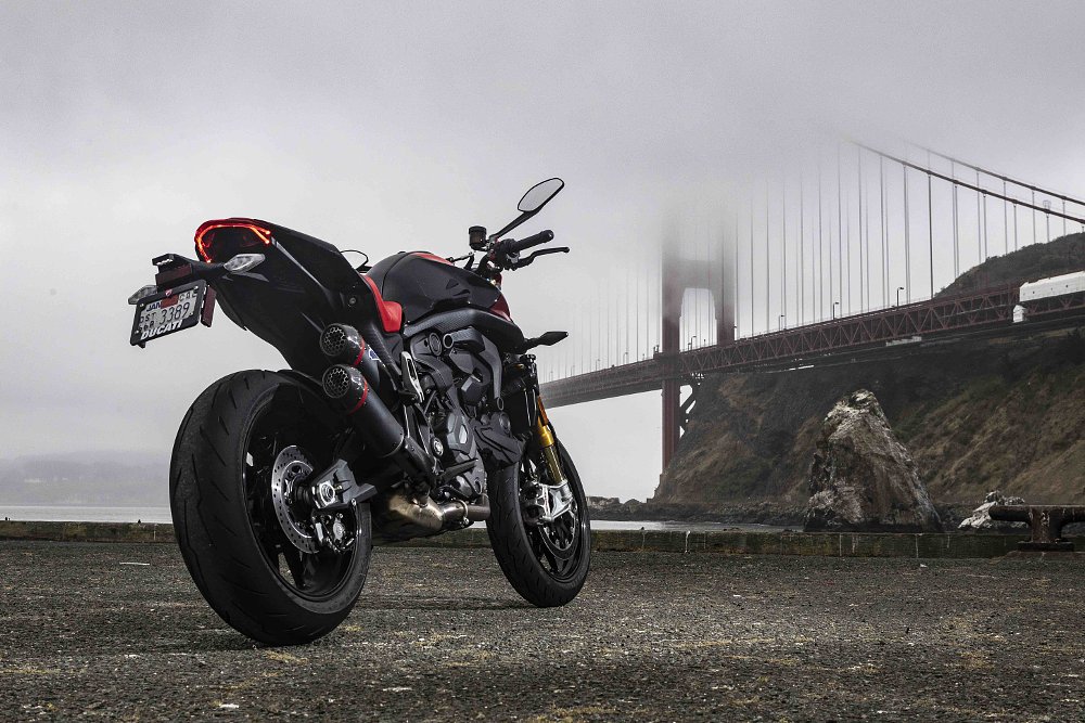 A rear three-quarter image of the 2024 Ducati Monster SP parked and the Golden Gate Bridge in the background.