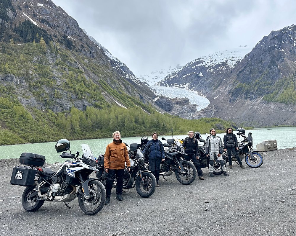 four riders and their motorcycles in front of the glacier in the background