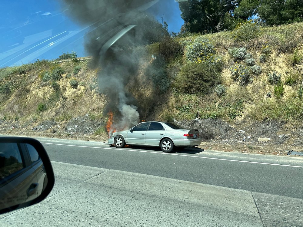 A Toyota Camry on fire on the side of the 405 freeway in Los Angeles.