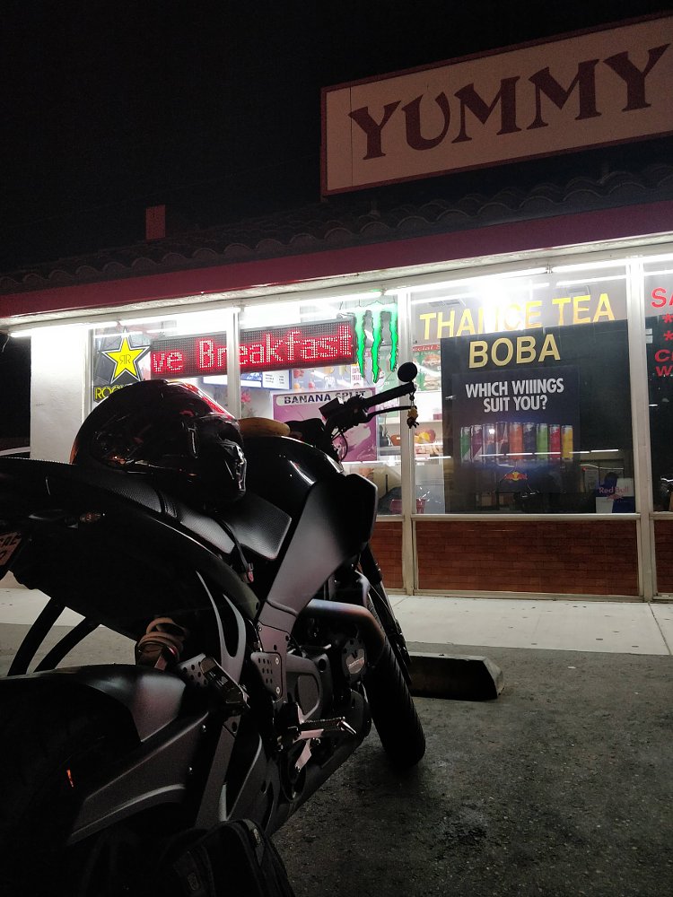 motorcycle parked in front of a shop with a sign saying Yummy