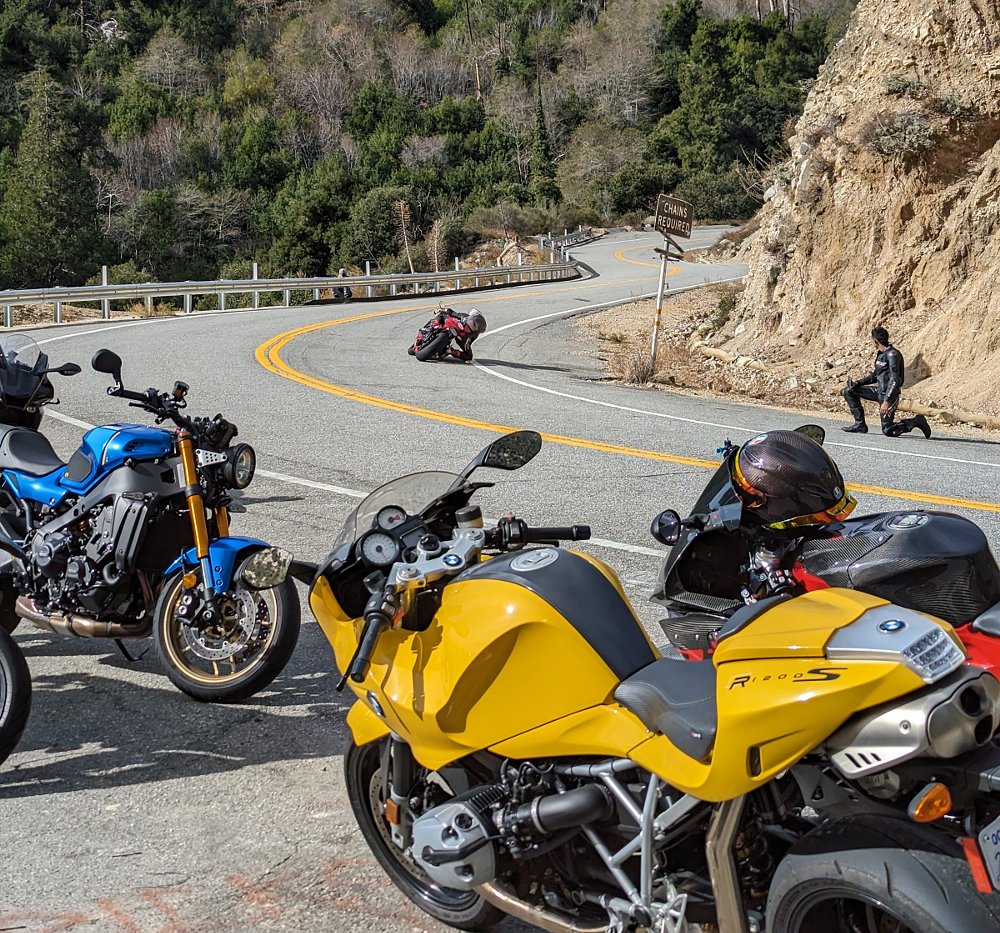 motorcycles parked by a California canyon road with a rider going by quickly