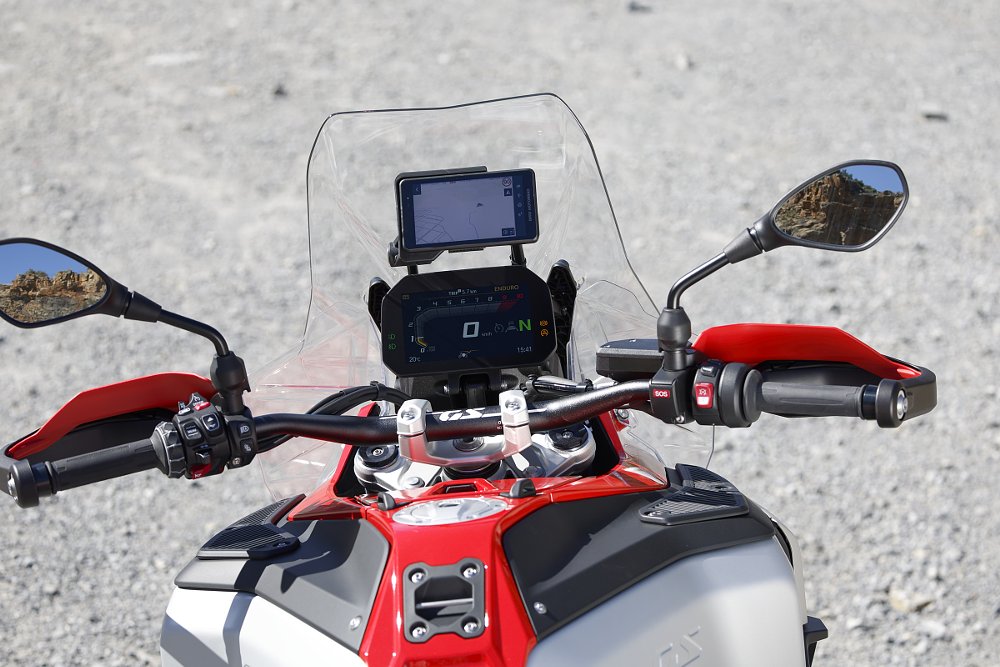 cockpit view of handlebar, display and a GPS unit mounted on a bracket above the display