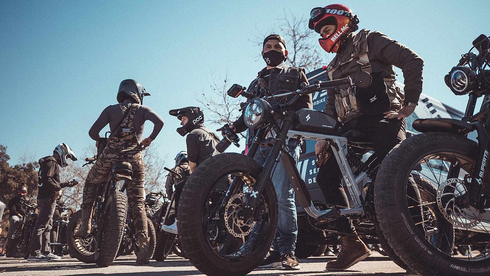 A group of e-bike riders mounted on Super73 models in a parking lot.