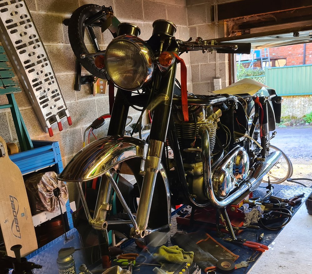 the old Norton motorcycle on a work stand in the garage, partially stripped down