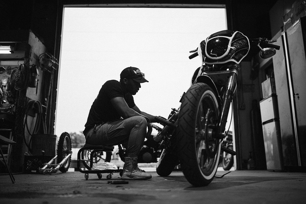 silhouette of a man working on a motorcycle in a garage