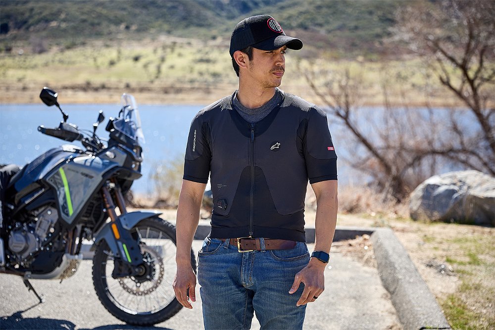 Dustin wears the Alpinestars Tech-Air 5 Plasma with the CFMOTO Ibex 450 and a lake in the background.