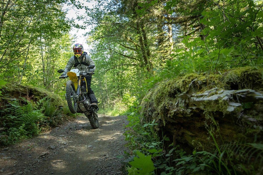 2025 Suzuki DR-Z4S wheelying over a bump in a trail.