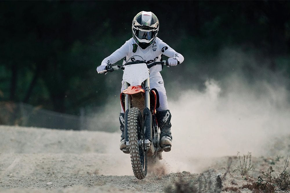 An off-road rider pushing the Stark Varg MX over a set of sandy whoops.