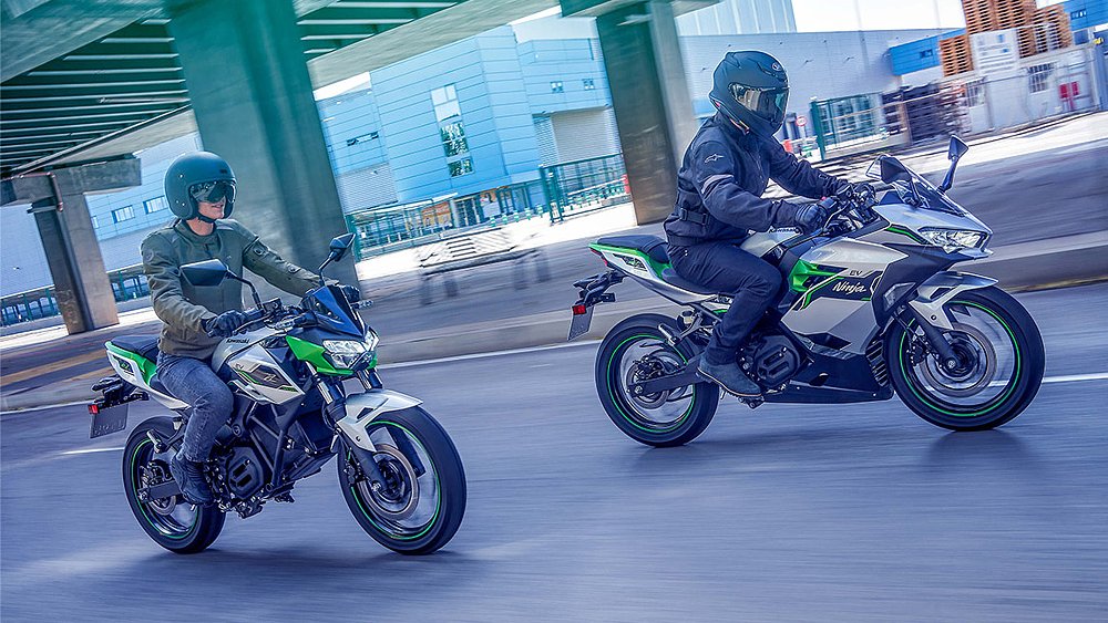 A male and female rider guide the Kawasaki Ninja e-1 and Z e-1 through an urban landscape.