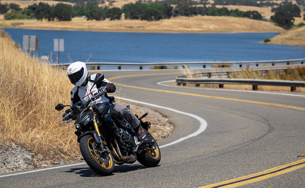 rider on the CB1000 SP Hornet on a curving road with a lake in the background