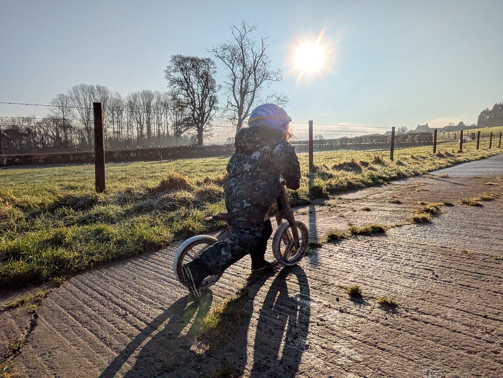 little girl riding her balance bike into the sunset on a path