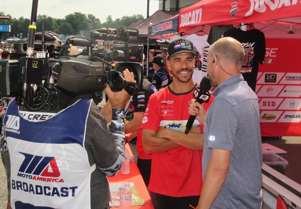 smiling Cameron Petersen dong an interview in front of the television camera in the pits at the race track