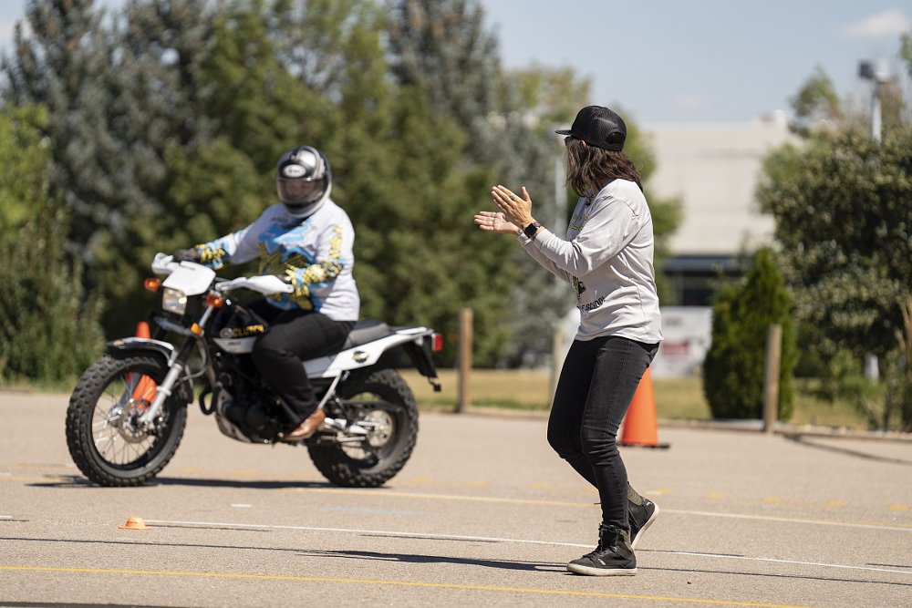female coach on the range cheering on a student on a small motorcycle